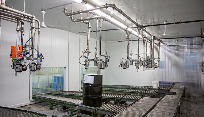 black drum on a conveyor belt being filled inside warehouse